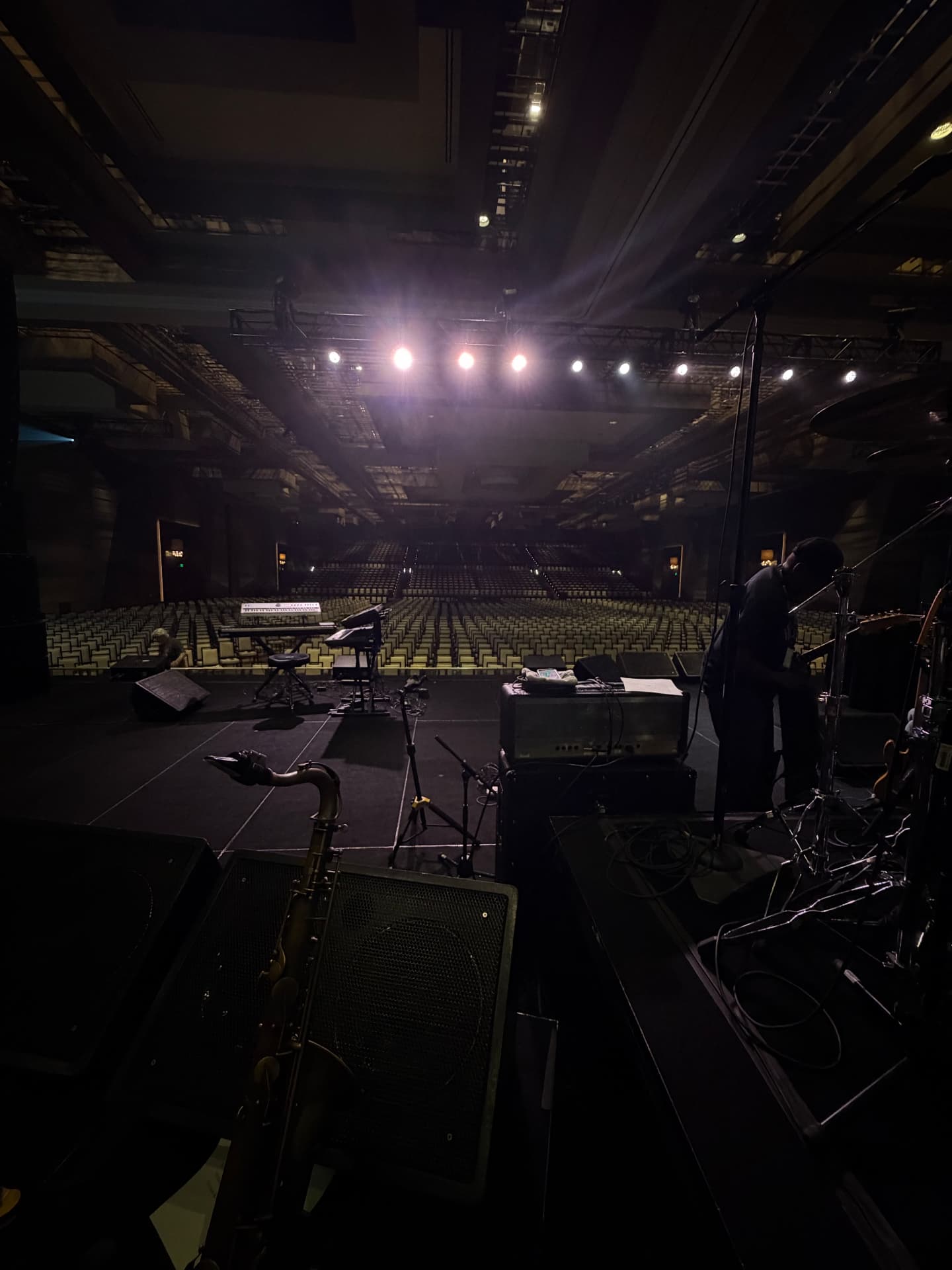 View from the stage of an empty theater house lit by overhead stage lights
