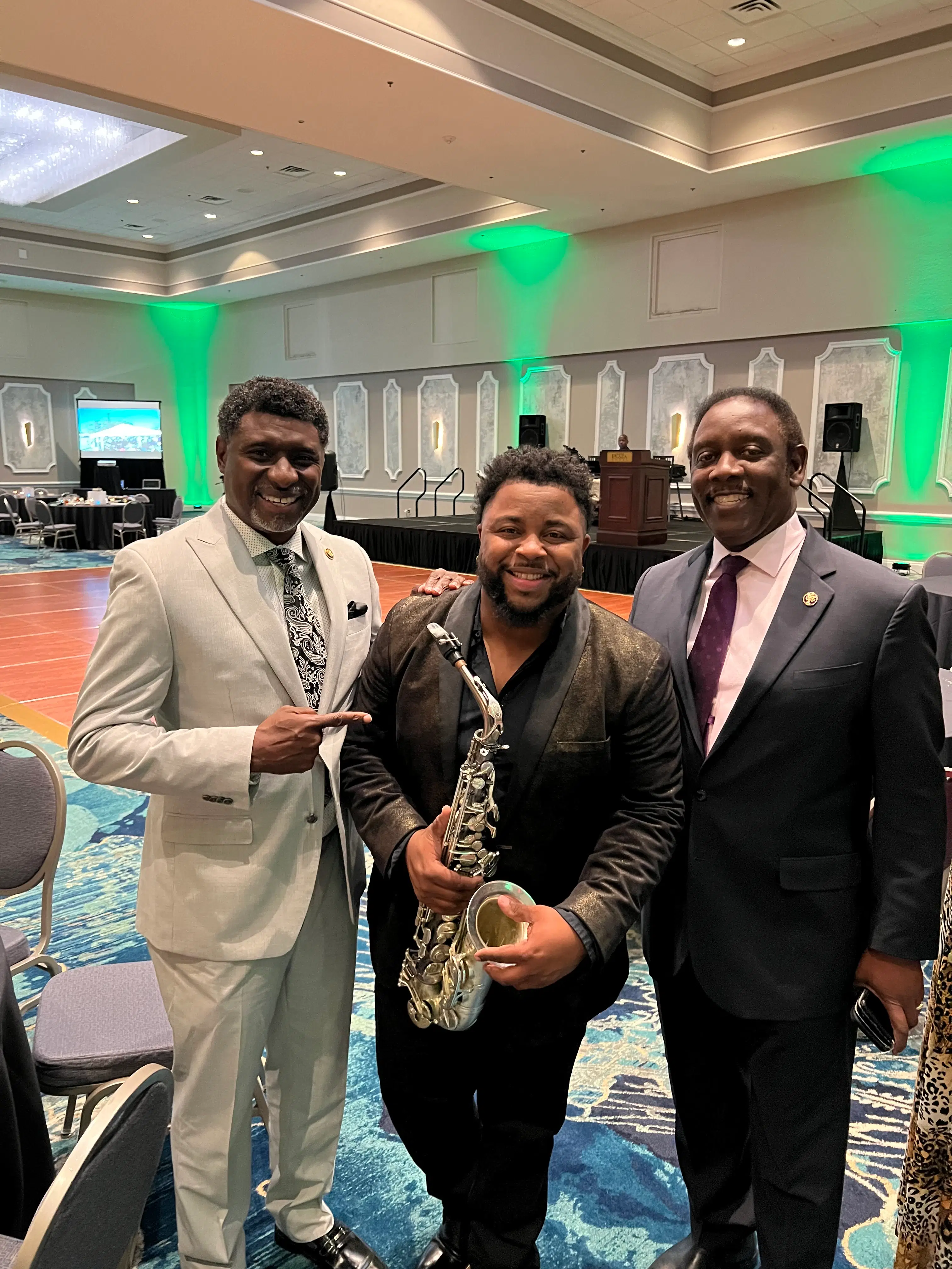 Dayve Stewart with civic leaders at a community event while holding his saxophone