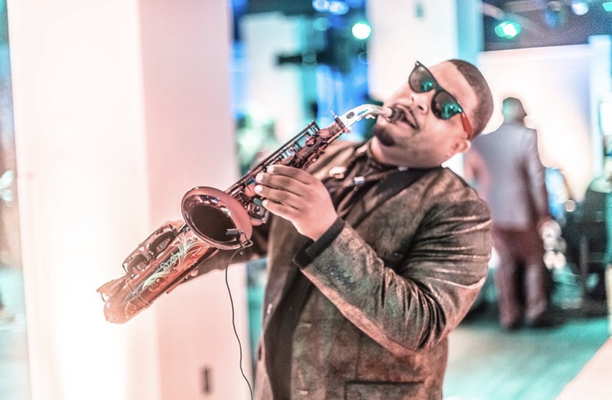Dayve Stewart playing a golden saxophone at an elegant wedding celebration