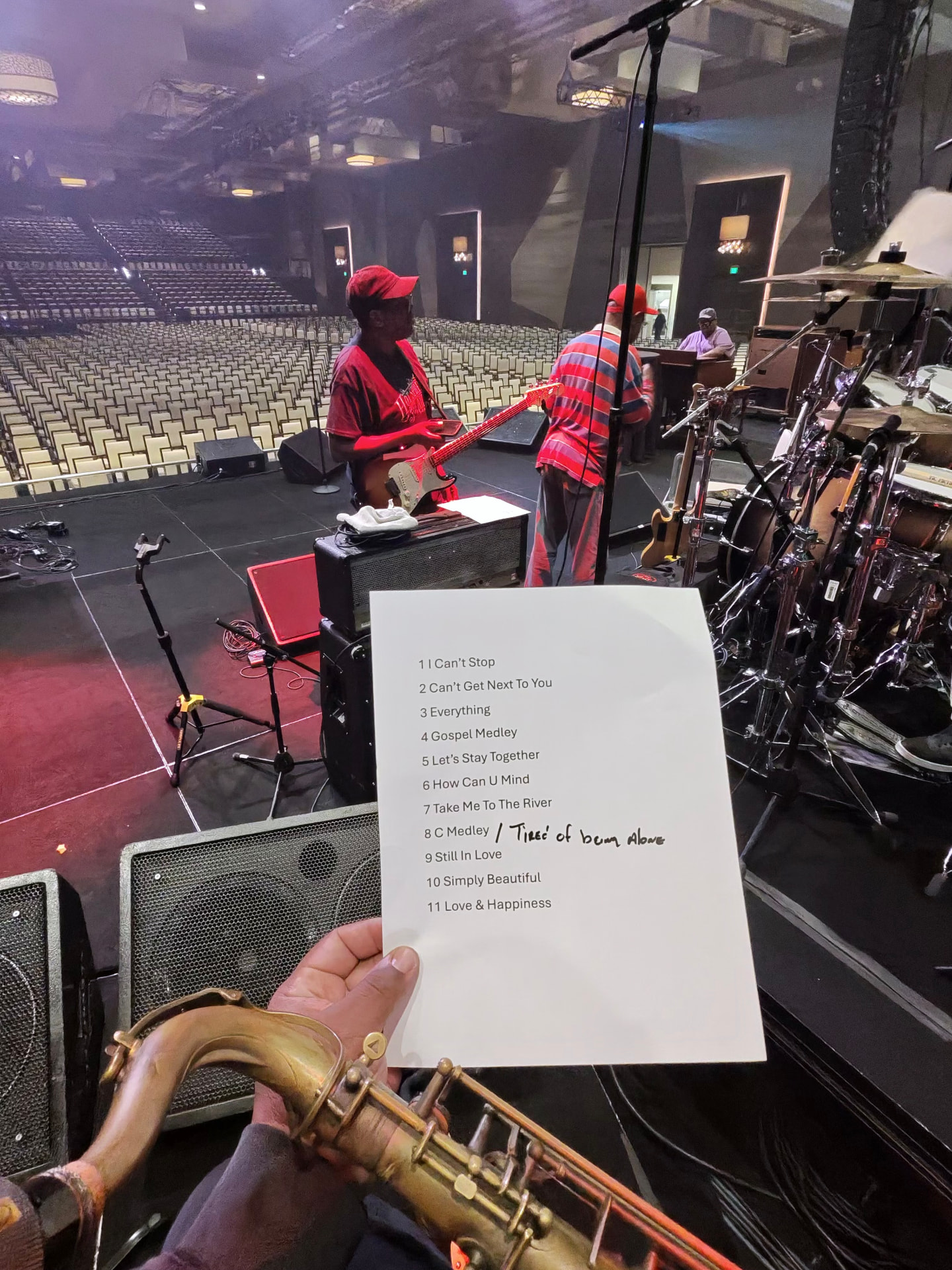 A hand holding tonight's setlist while the band sets up behind it