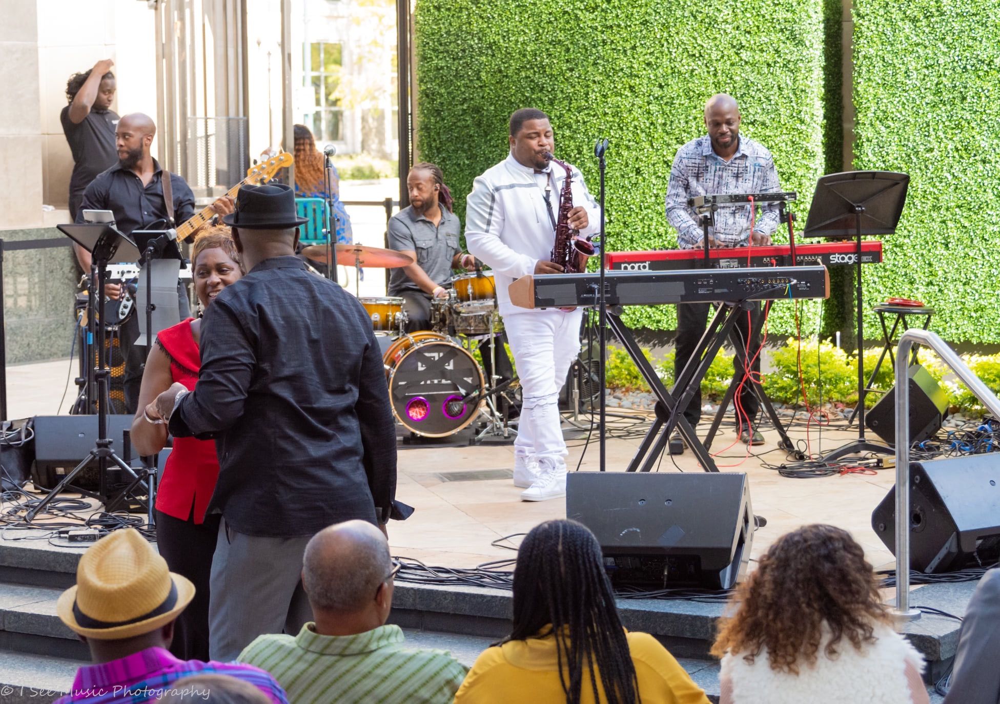 Dayve Stewart performing saxophone with a live ensemble outdoors before an audience